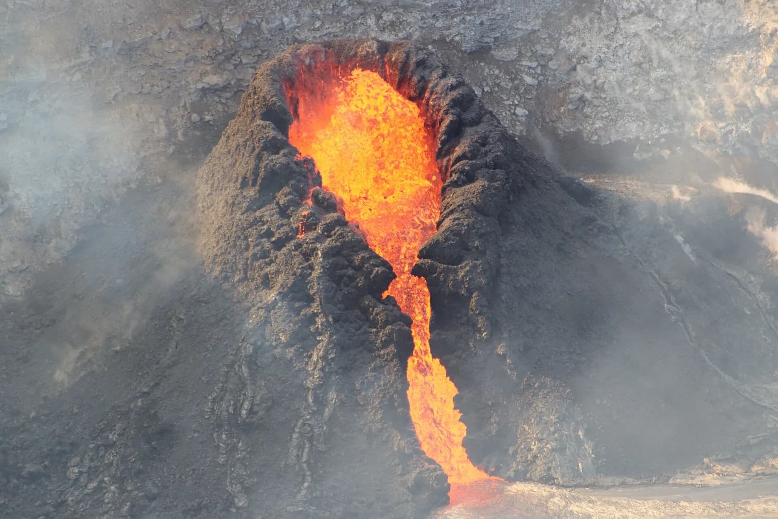 Lava fountains at a fissure in Halemaʻumaʻu crater, with lava flowing through a channel toward the lava lake.