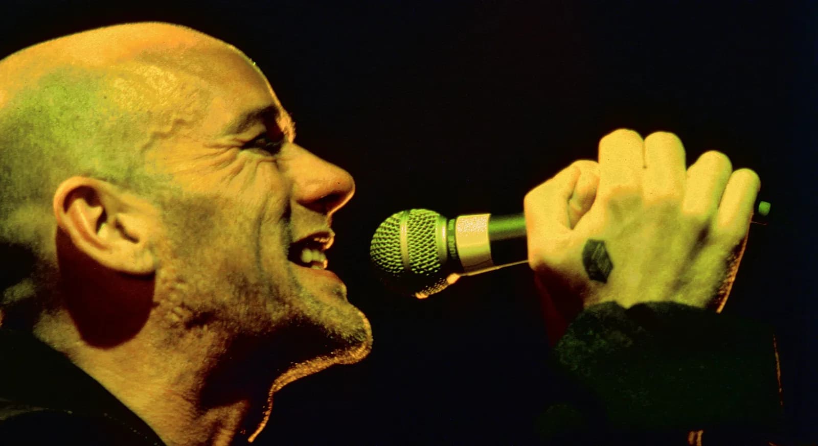Michael Stipe performing with a microphone at Sport Hall Bonifika in Koper, Slovenia.