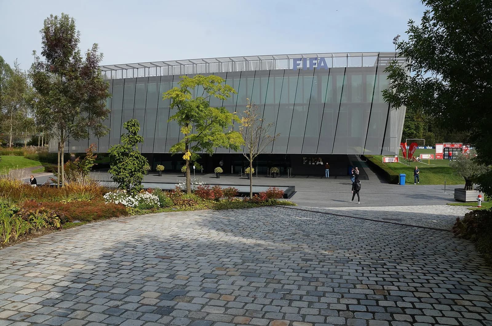 Exterior of FIFA’s headquarters in Zurich, a modern building with a wide glazed upper floor and landscaped grounds.
