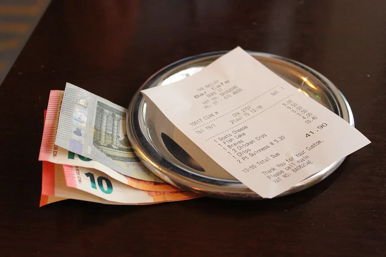 Restaurant bill with euro banknotes beside it