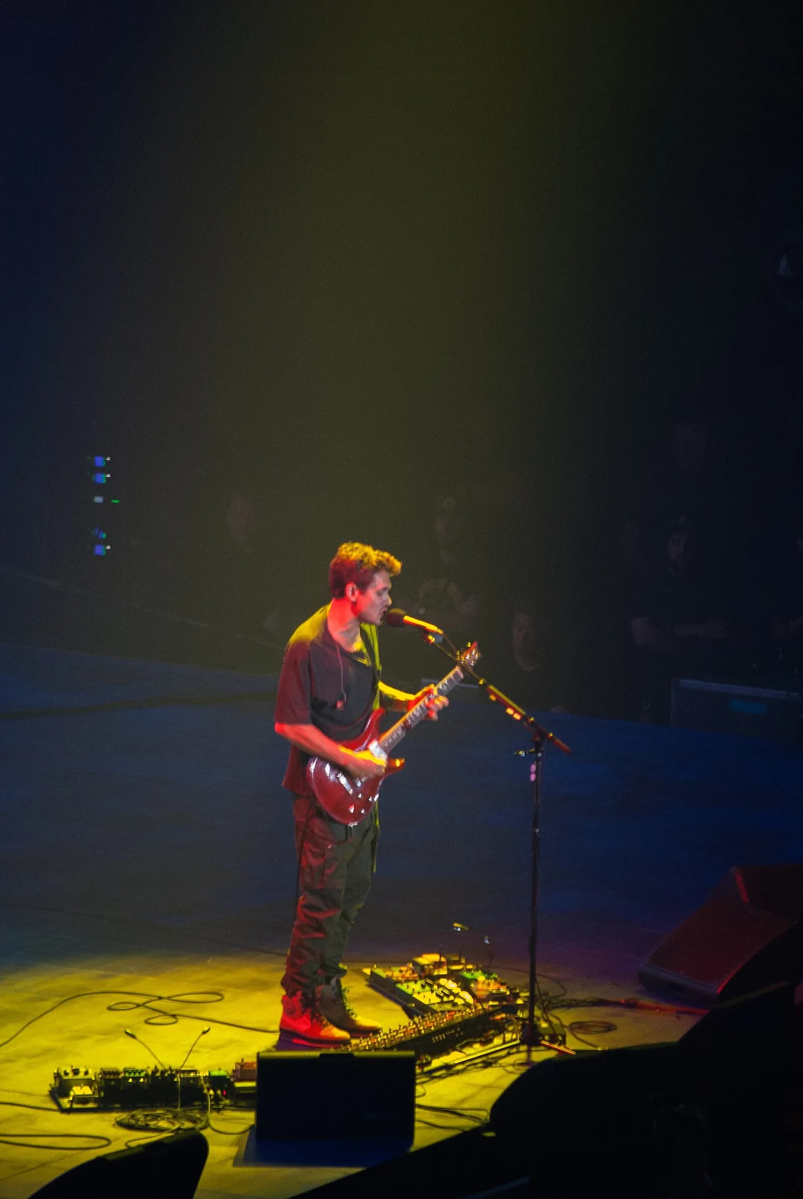 John Mayer performing onstage with a guitar.