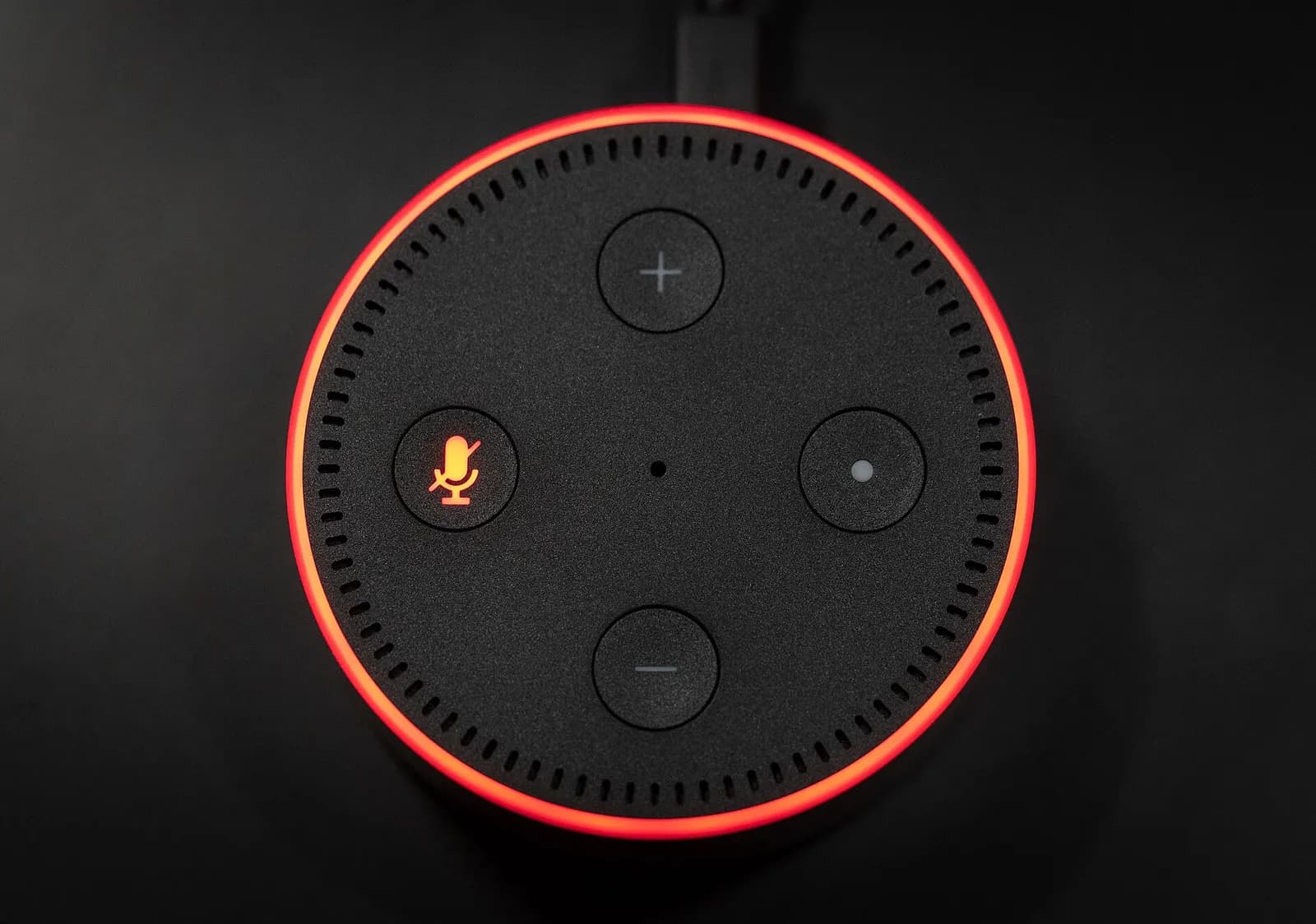 An Amazon Echo Dot speaker with its microphone disabled, indicated by a red ring and illuminated microphone light.