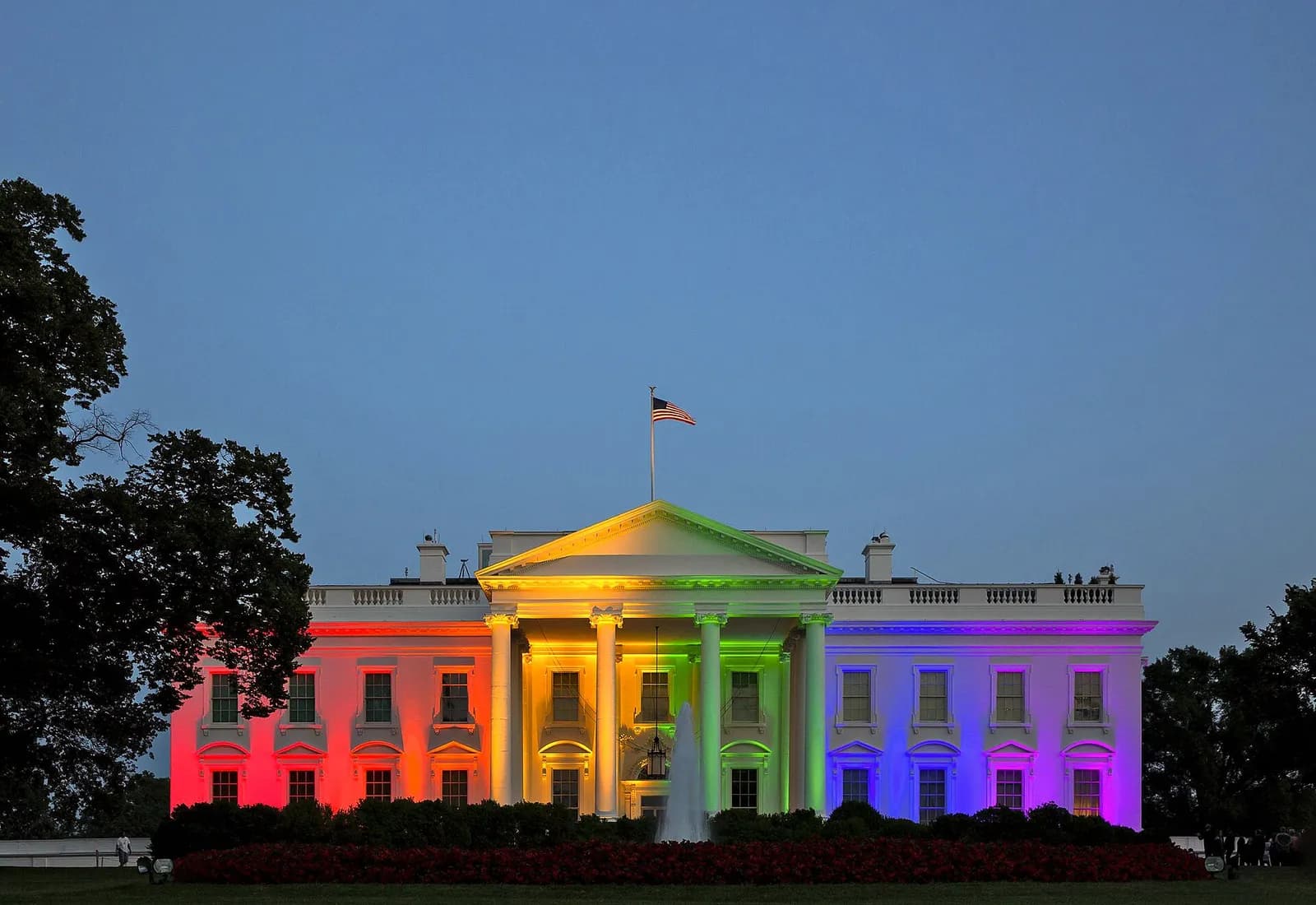 The White House illuminated in rainbow colors at night.