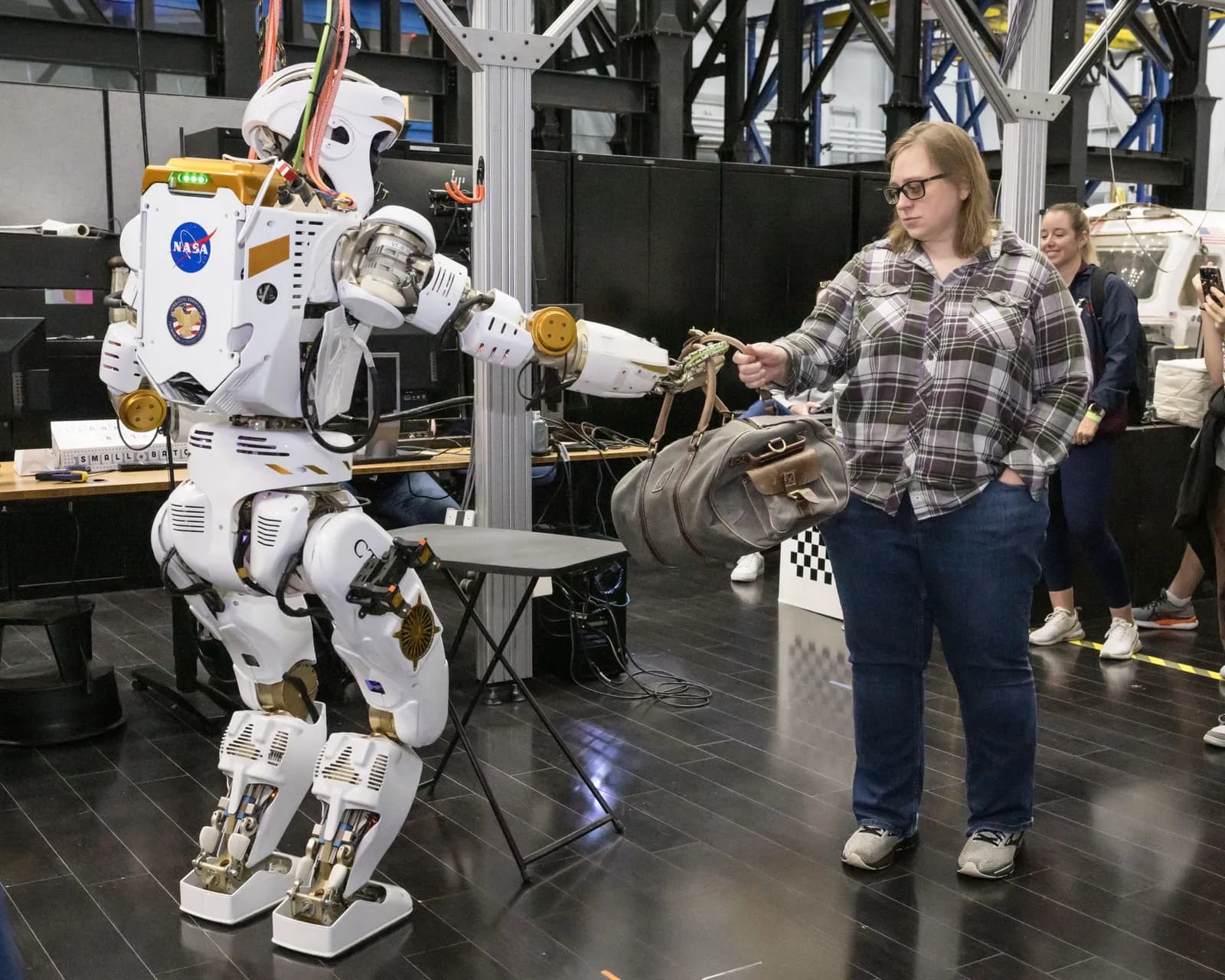NASA’s Valkyrie humanoid robot hands a duffel bag to Dexterous Robotics Team member Emily Sheetz.