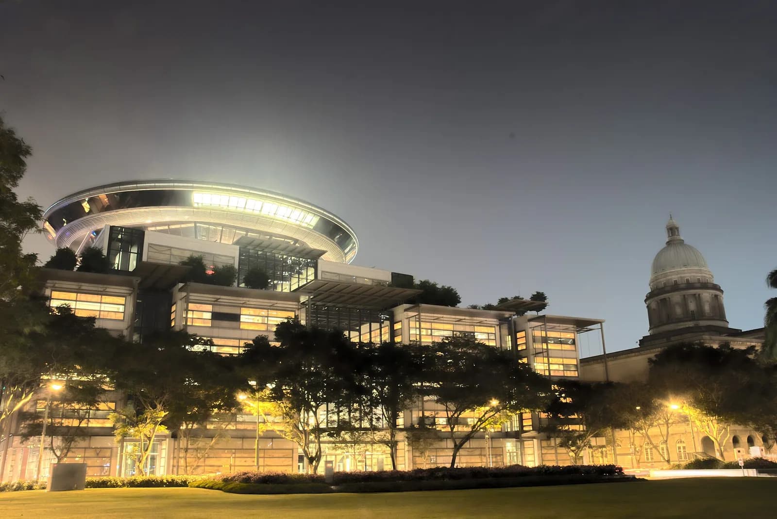 The old and new Supreme Court buildings in Singapore at night.