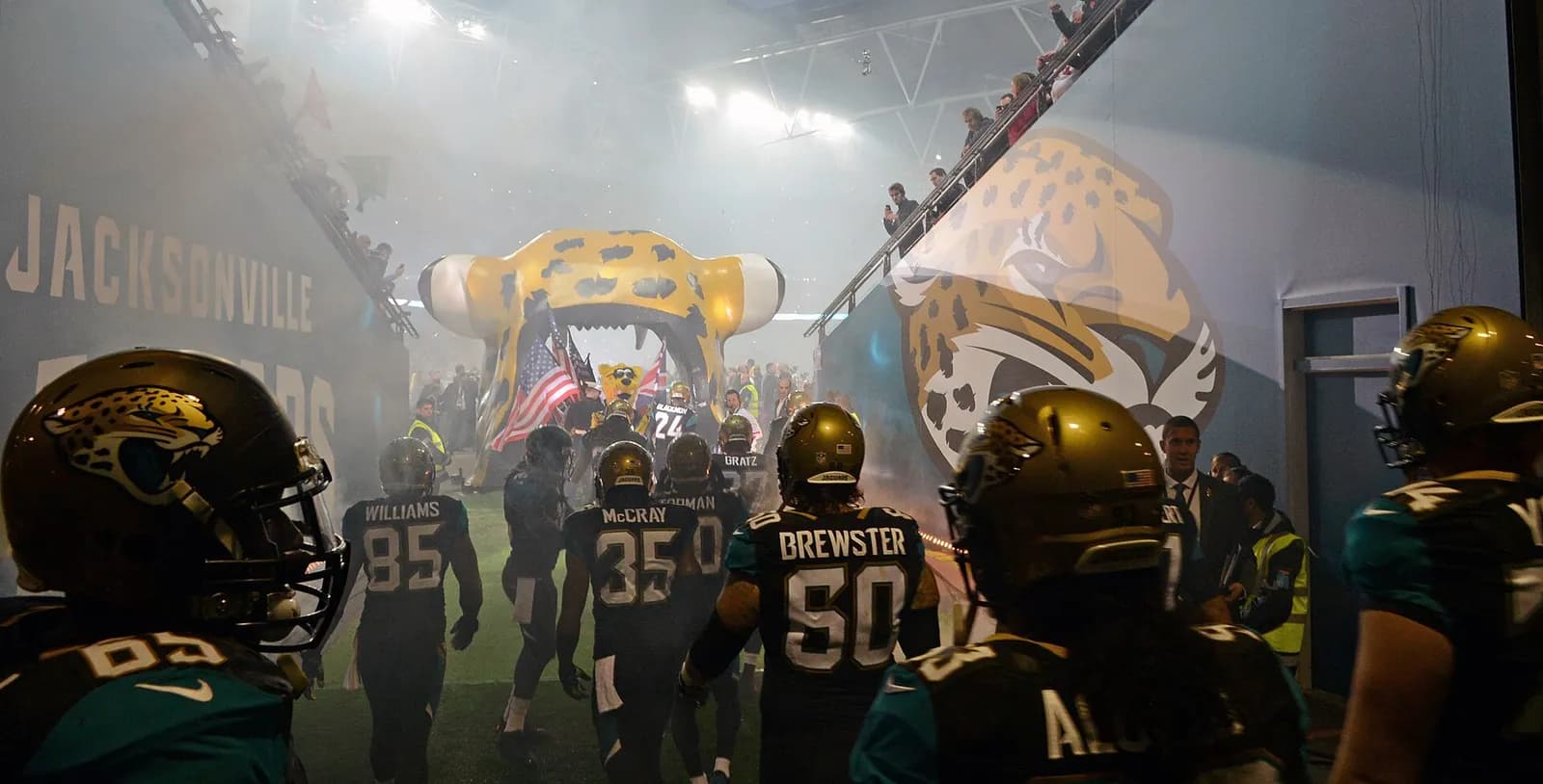 Jacksonville Jaguars players prepare to take the field at Wembley Stadium in London, with an airman holding an American flag at the front of the formation.