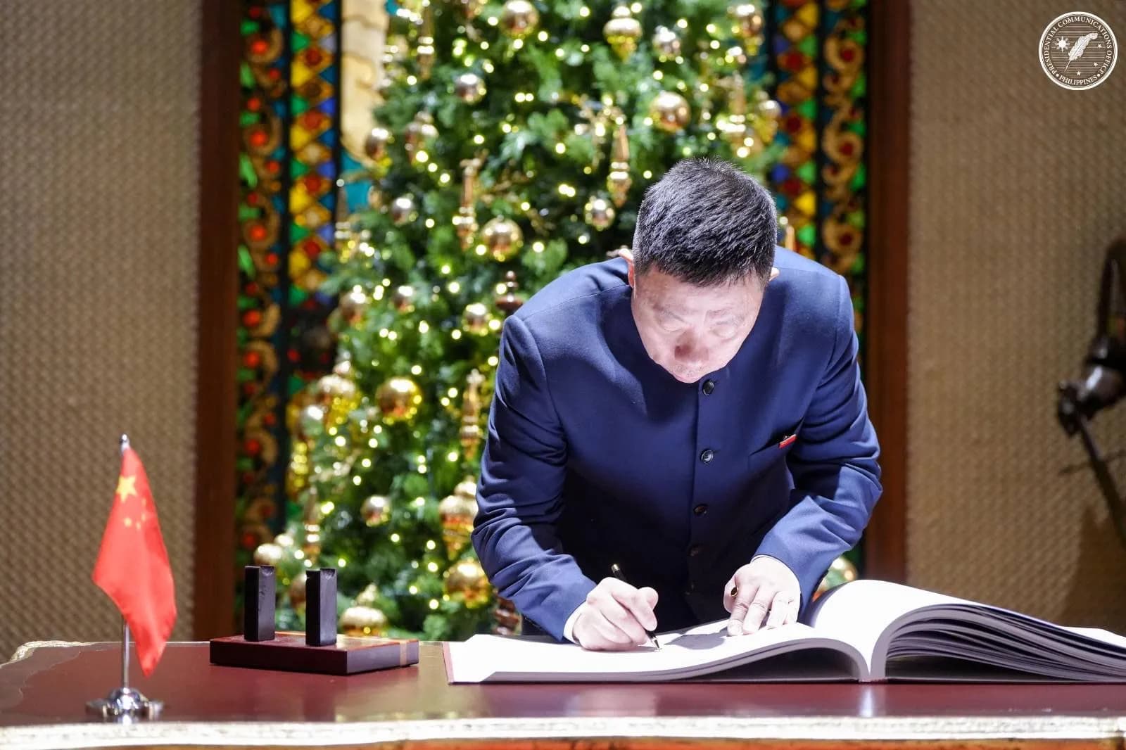 Chinese Ambassador Jing Quan signing a book on December 11, 2025.