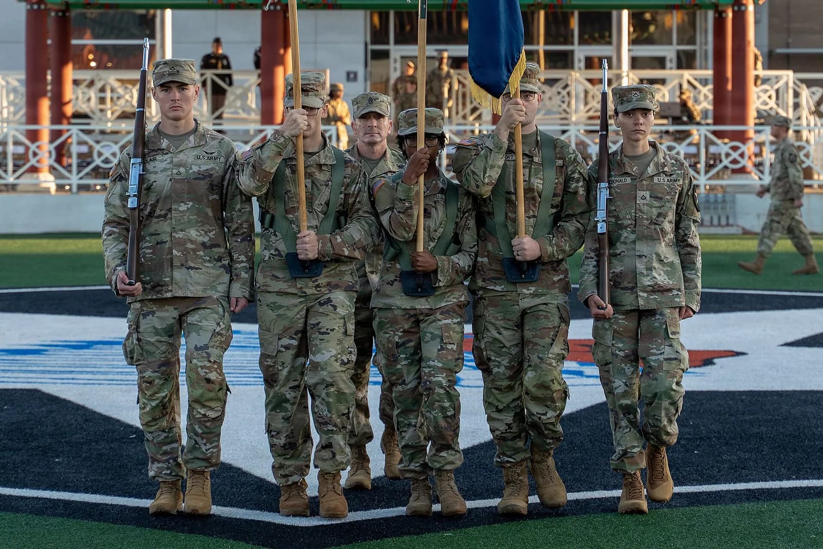 U.S. Army color guard members march in formation, carrying rifles and flags, at Camp Humphreys.