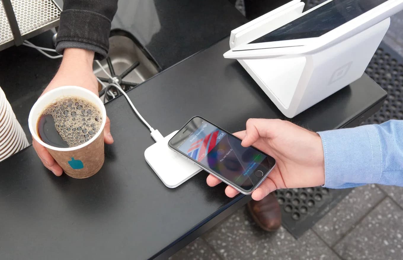 A shopper pays for coffee with an iPhone using a Square contactless reader.
