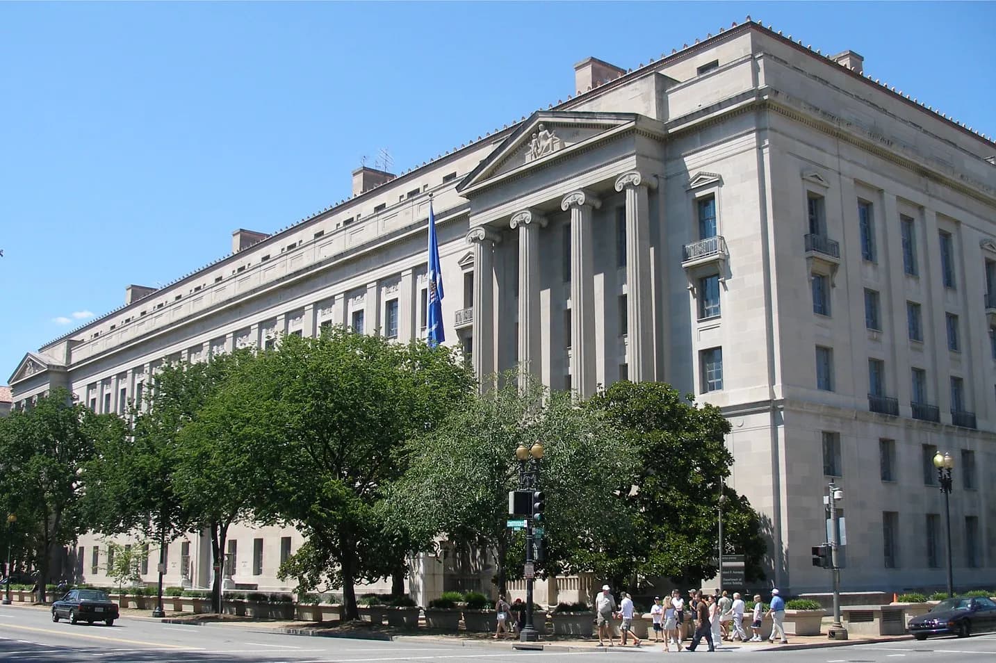The Robert F. Kennedy Department of Justice Building in Washington, D.C., with a U.S. Department of Justice flag in front.
