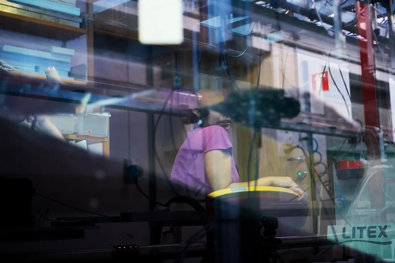 A researcher watches a wave move through an indoor experimental tank.