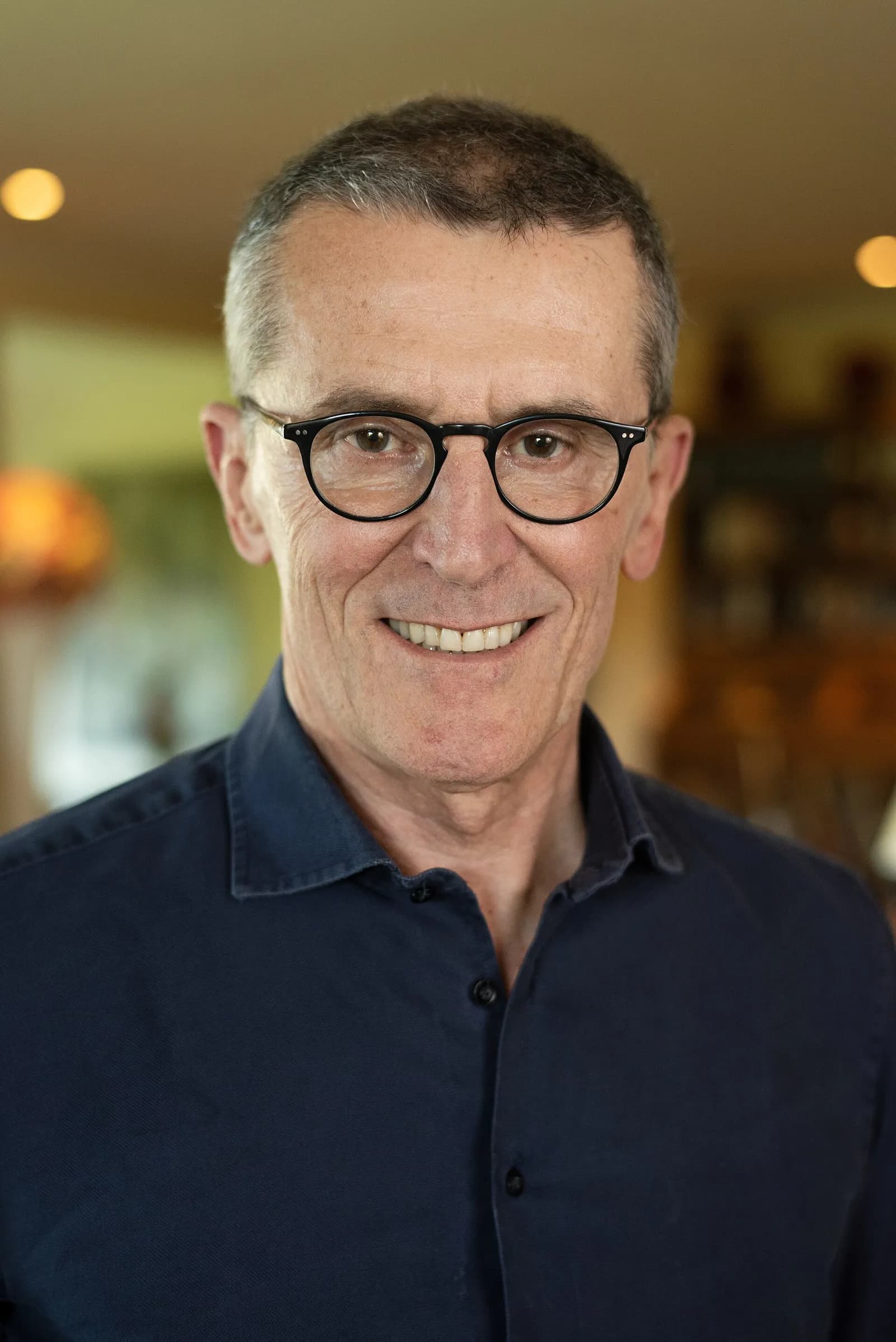 Portrait of Marco Bassetti, wearing glasses and a dark shirt.