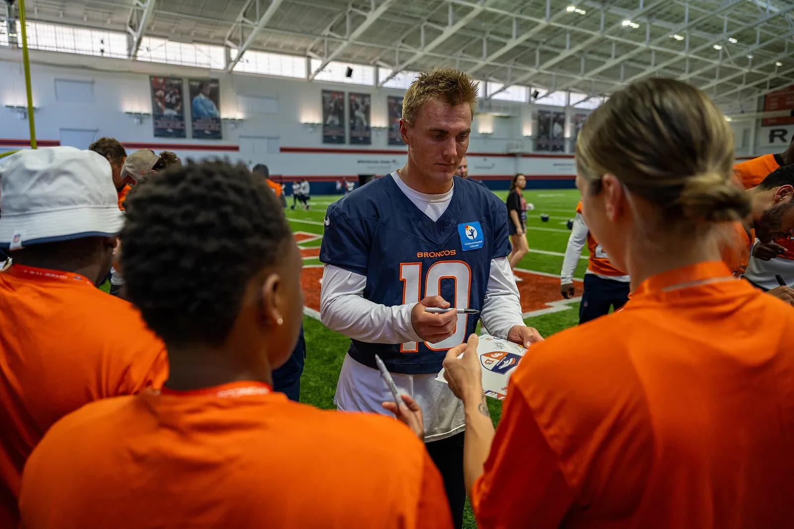 Denver Broncos quarterback Bo Nix signs autographs for service members at Broncos Park.