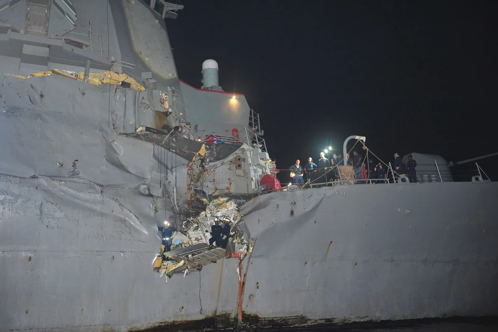 The damaged bow of guided-missile destroyer USS Porter, with sailors aboard, at sea.