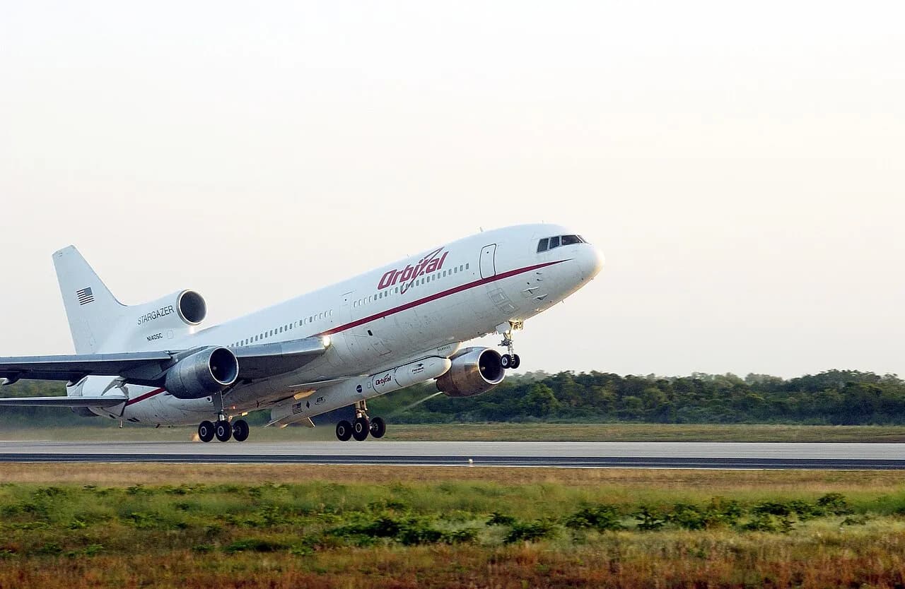 An L-1011 aircraft takes off carrying a Pegasus rocket with the GALEX satellite beneath it.