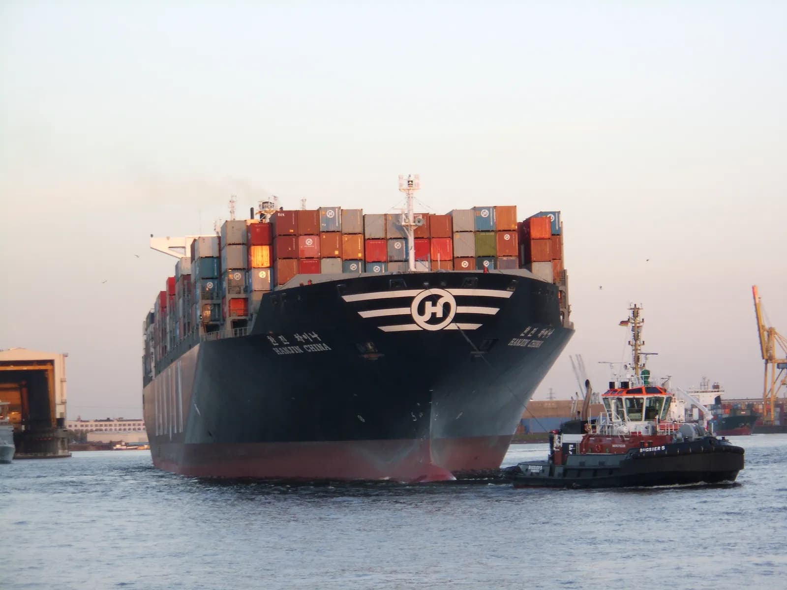 The container ship Hanjin China alongside a tugboat in Hamburg harbor.