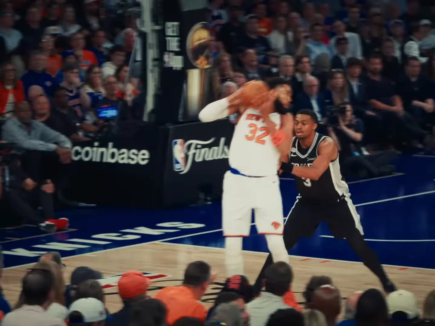 New York Knicks player Karl-Anthony Towns guarded by San Antonio Spurs player Keldon Johnson during a basketball game.