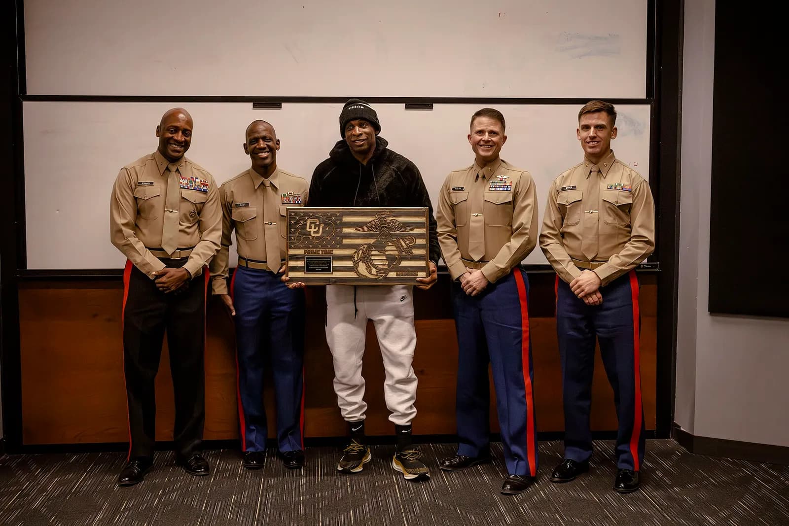 Deion Sanders stands with U.S. Marines during a presentation in Boulder.