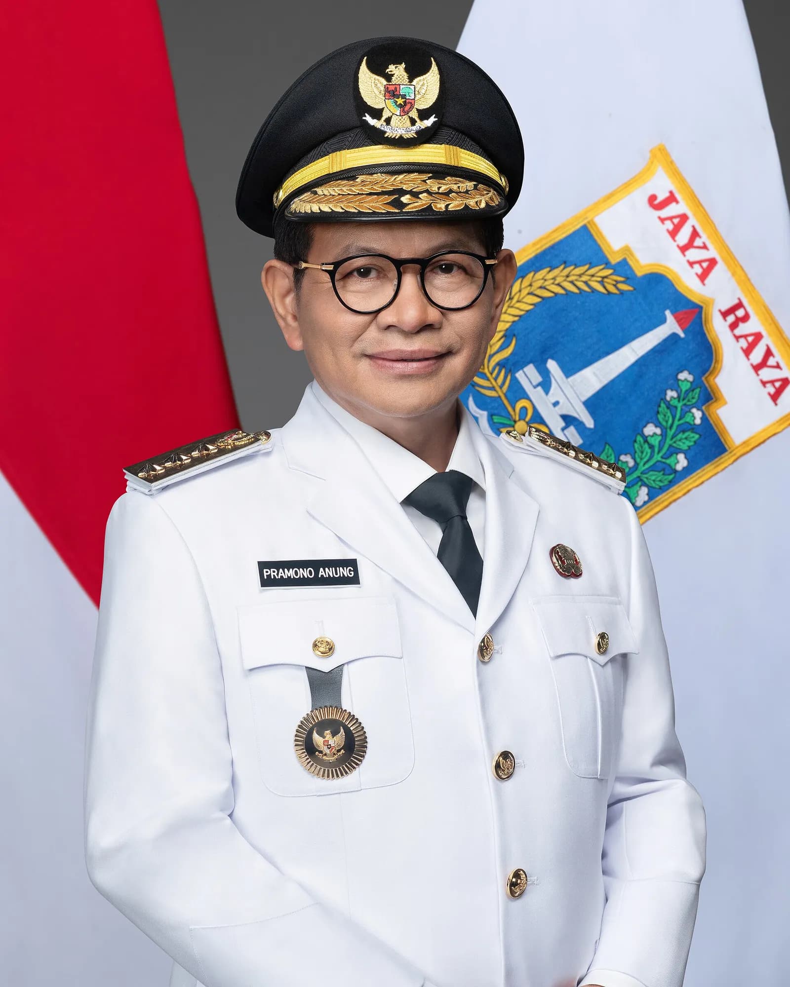 Jakarta Governor Pramono Anung standing in front of the Indonesian flag.