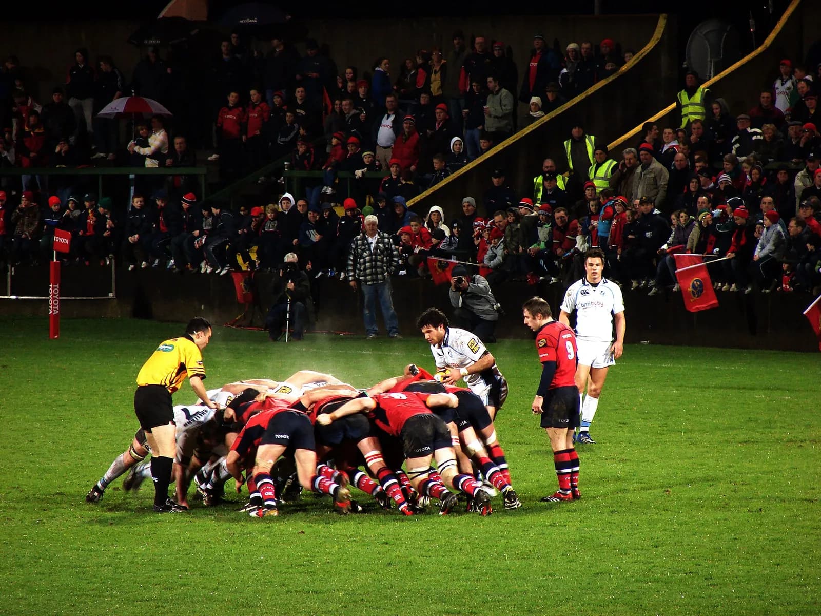 Players from Munster and Cardiff contest a scrum during a rugby match.