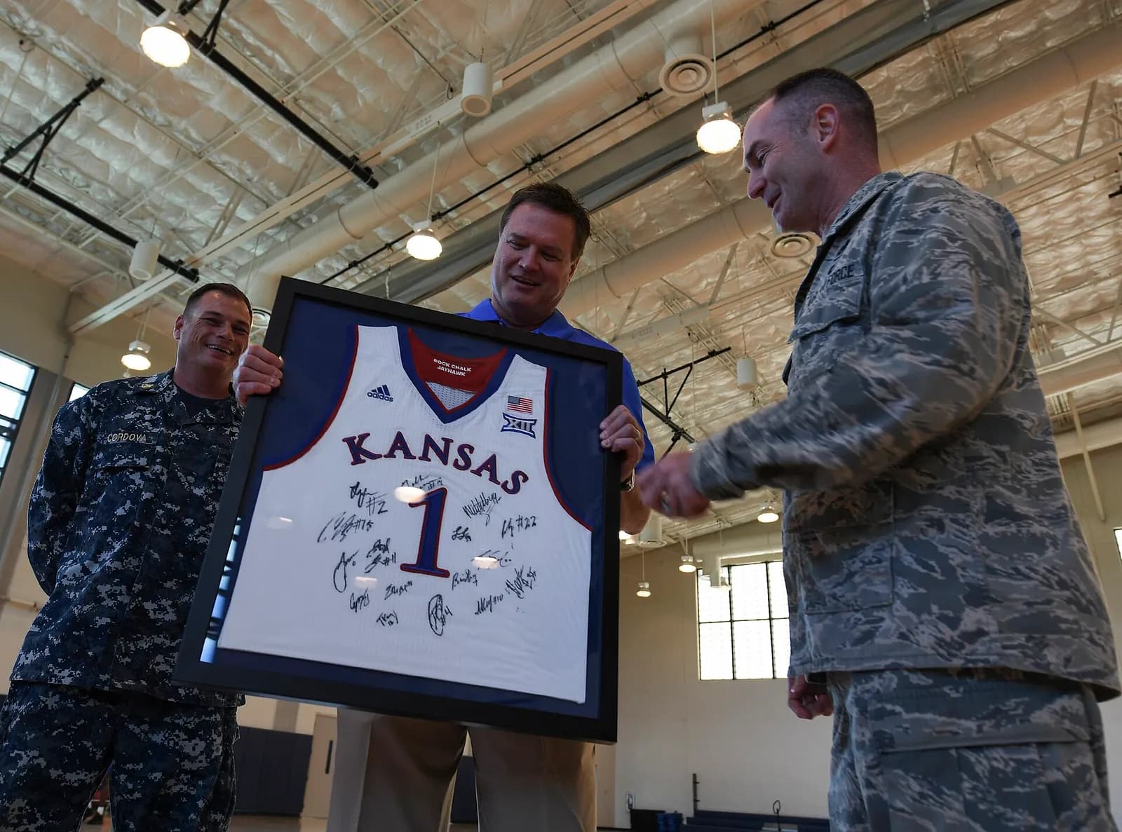 Bill Self presents a framed Kansas Jayhawks jersey to Air Force Col. Renzy Smith during a team practice.