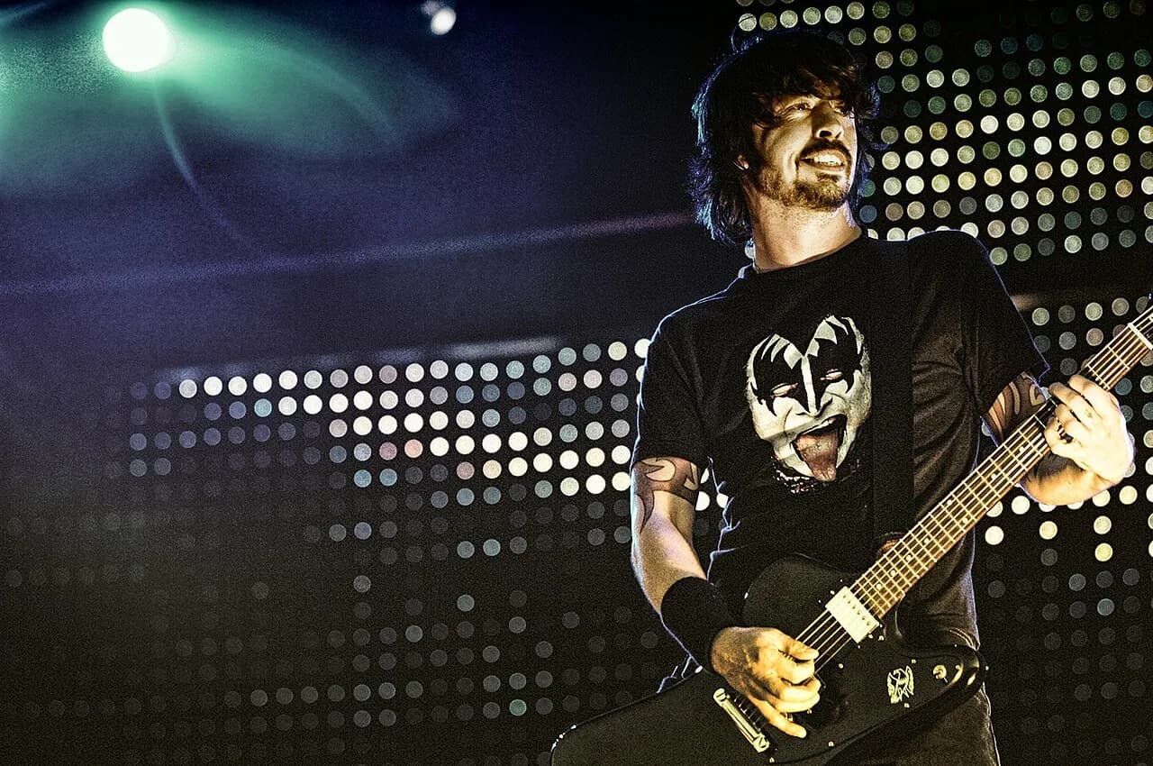 Dave Grohl performing onstage with a guitar in an earlier photograph