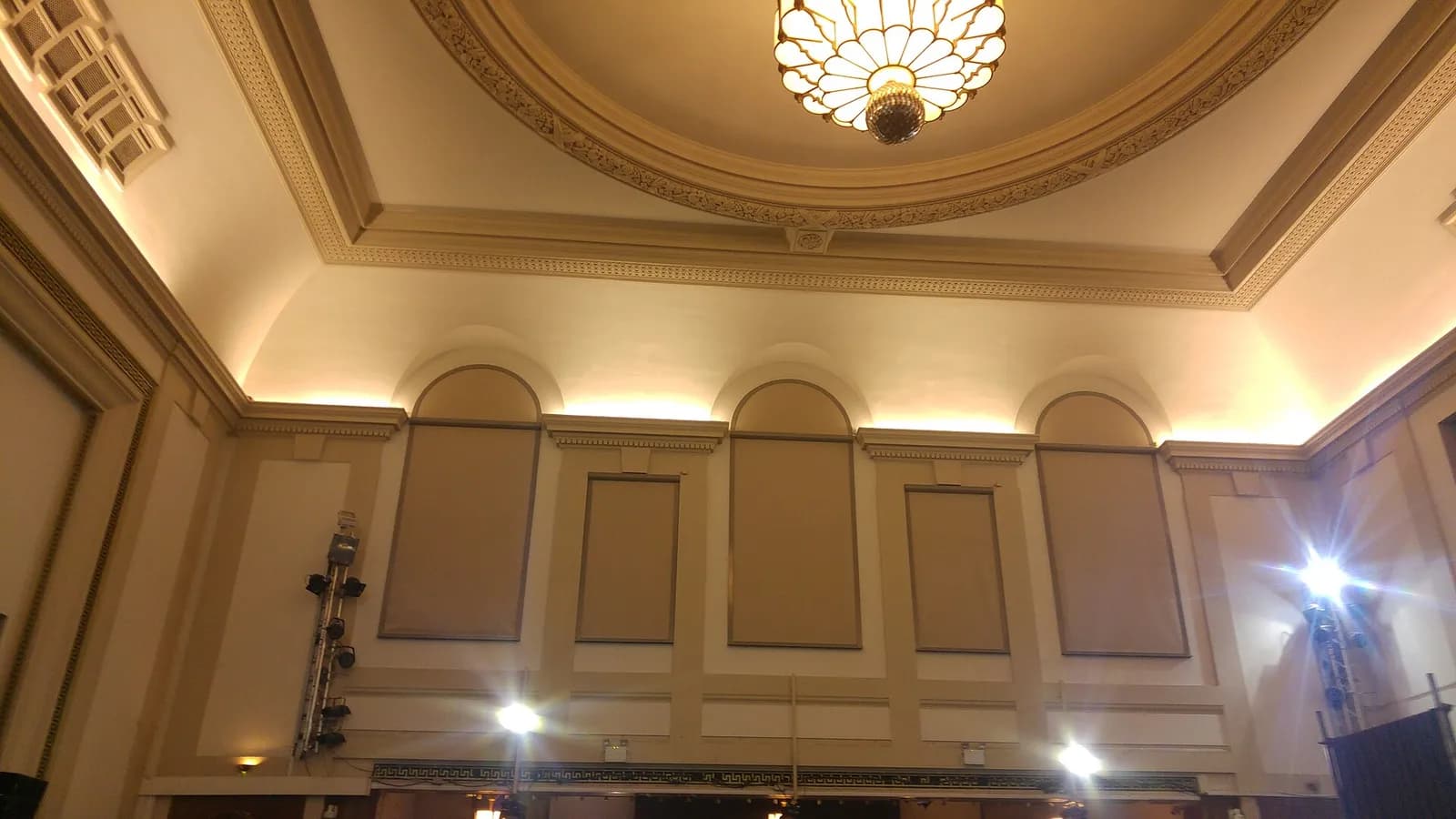 The ornate upper walls and ceiling of Camden Centre, with decorative molding and a large chandelier.