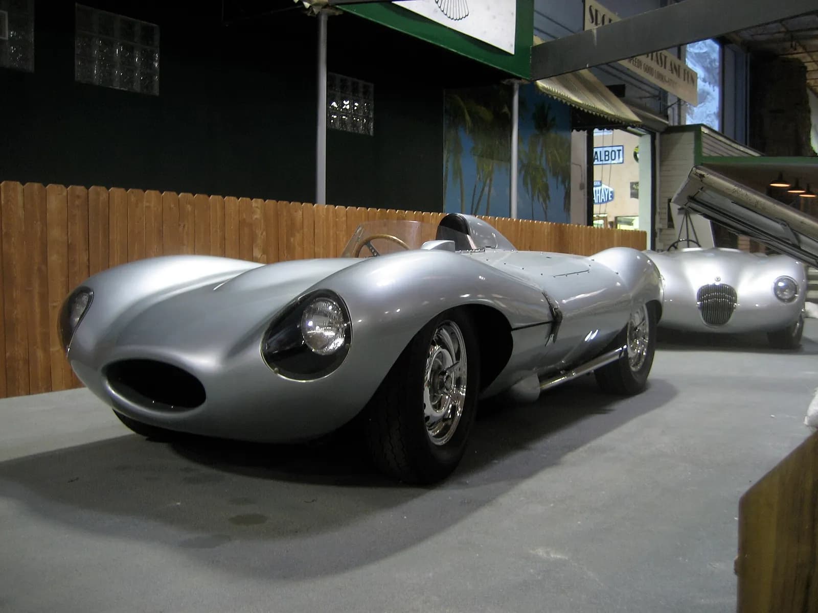 Two classic Jaguar racing cars displayed in a museum.