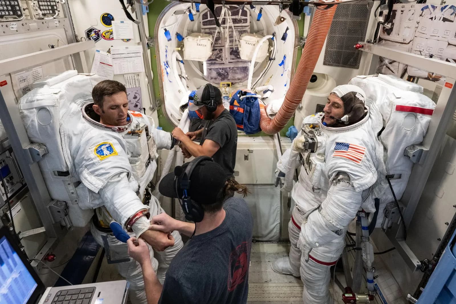 Crew-13 astronauts Joshua Kutryk and Luke Delaney practise putting on spacesuits with training specialists in a space station airlock simulator.