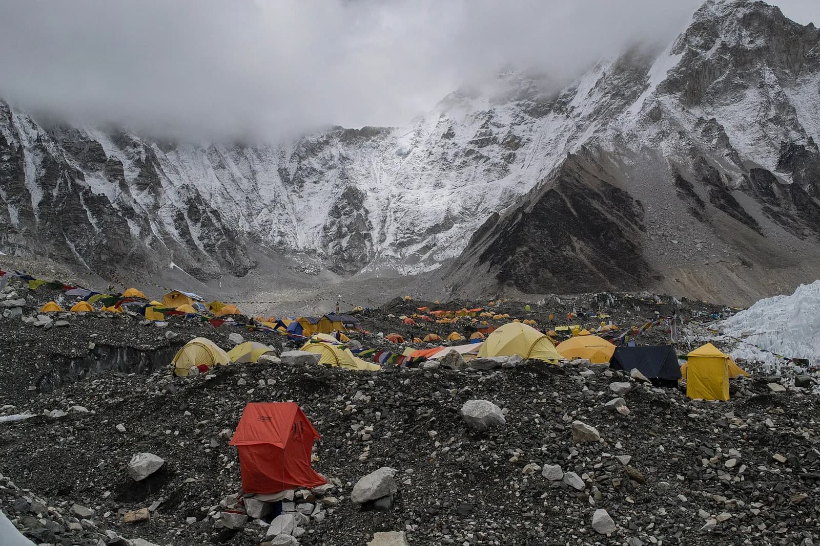 Everest Base Camp beneath dark storm clouds, with tents at the foot of the mountain.