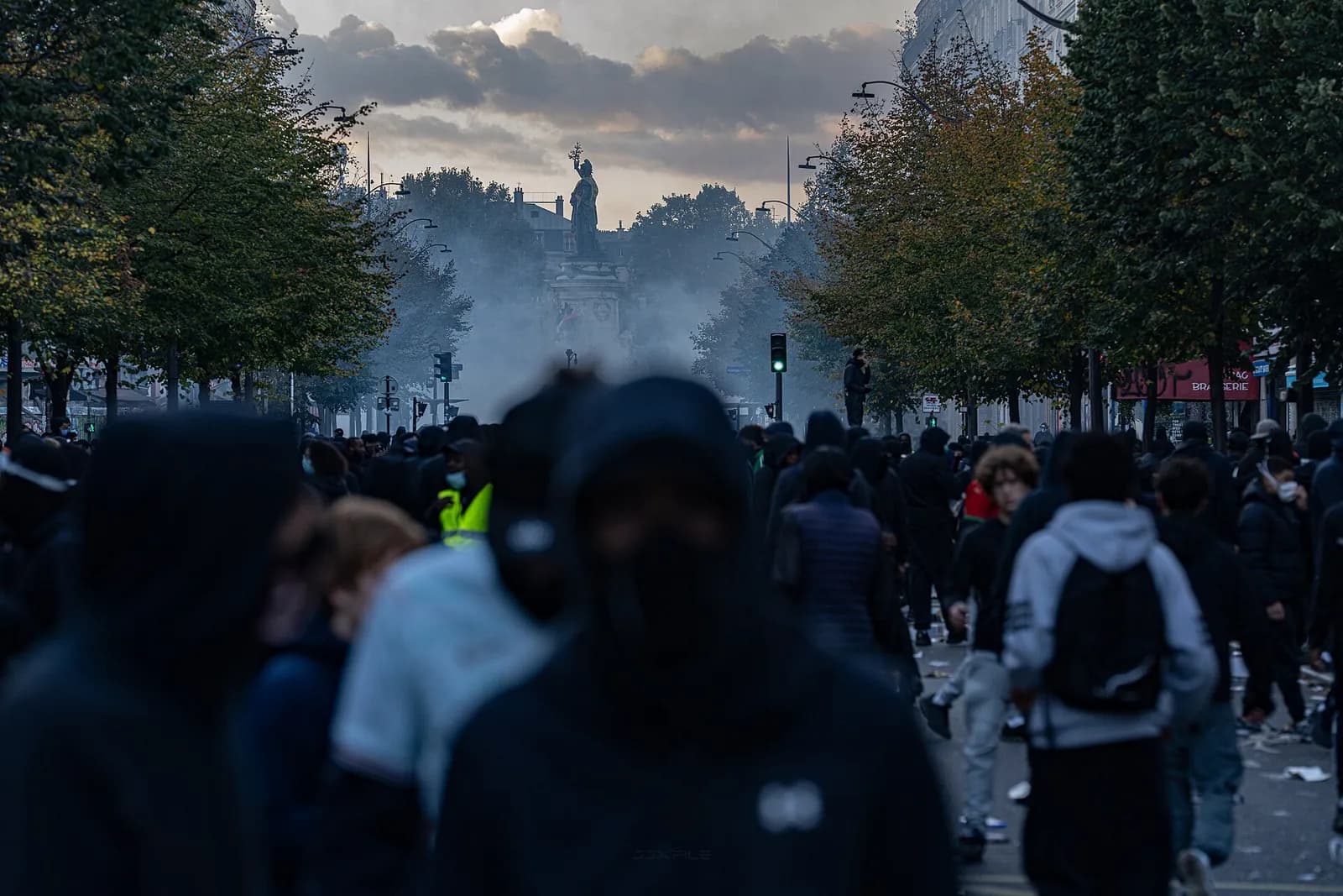 Protesters face tear gas on the boulevard leading to Place de la République in Paris, with the Monument to the Republic behind them.