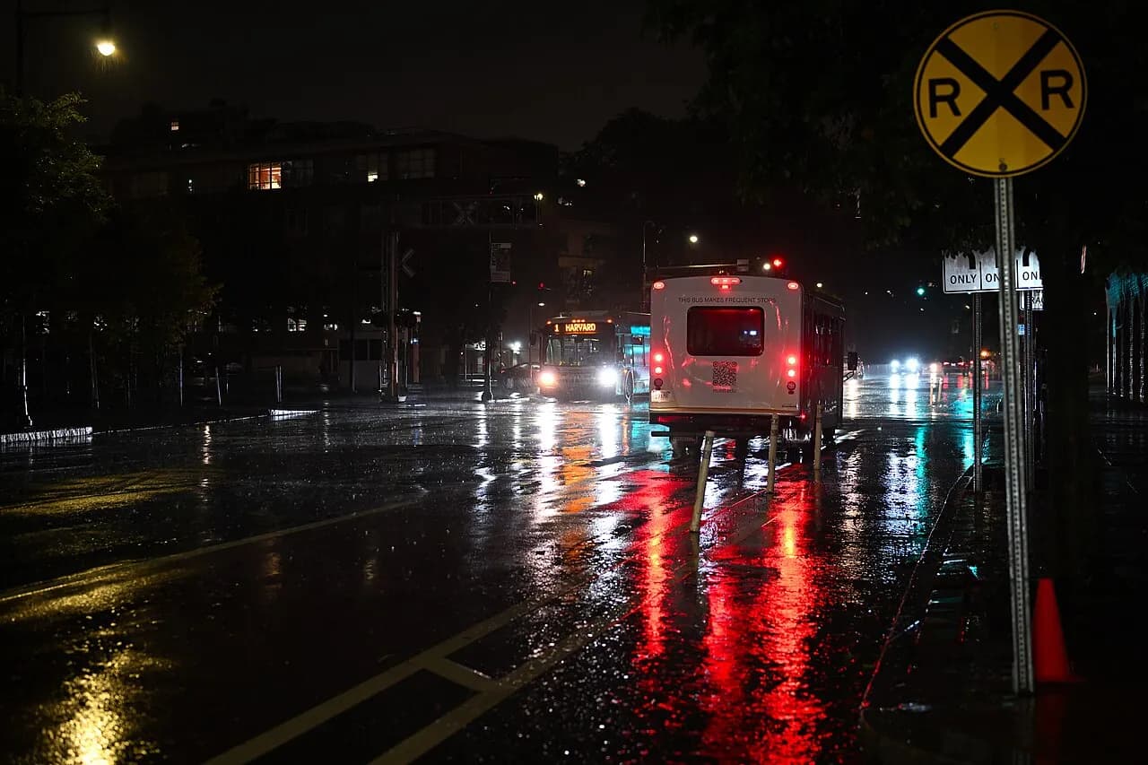 An MBTA route 1 bus and an MIT shuttle bus stopped near railroad tracks on Massachusetts Avenue in Cambridge