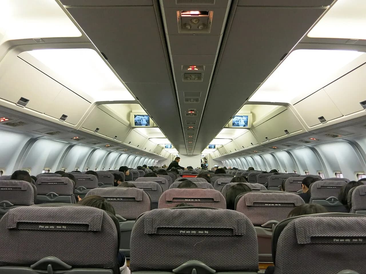 View from the back of a Qantas aircraft cabin, looking forward along the rows of seats