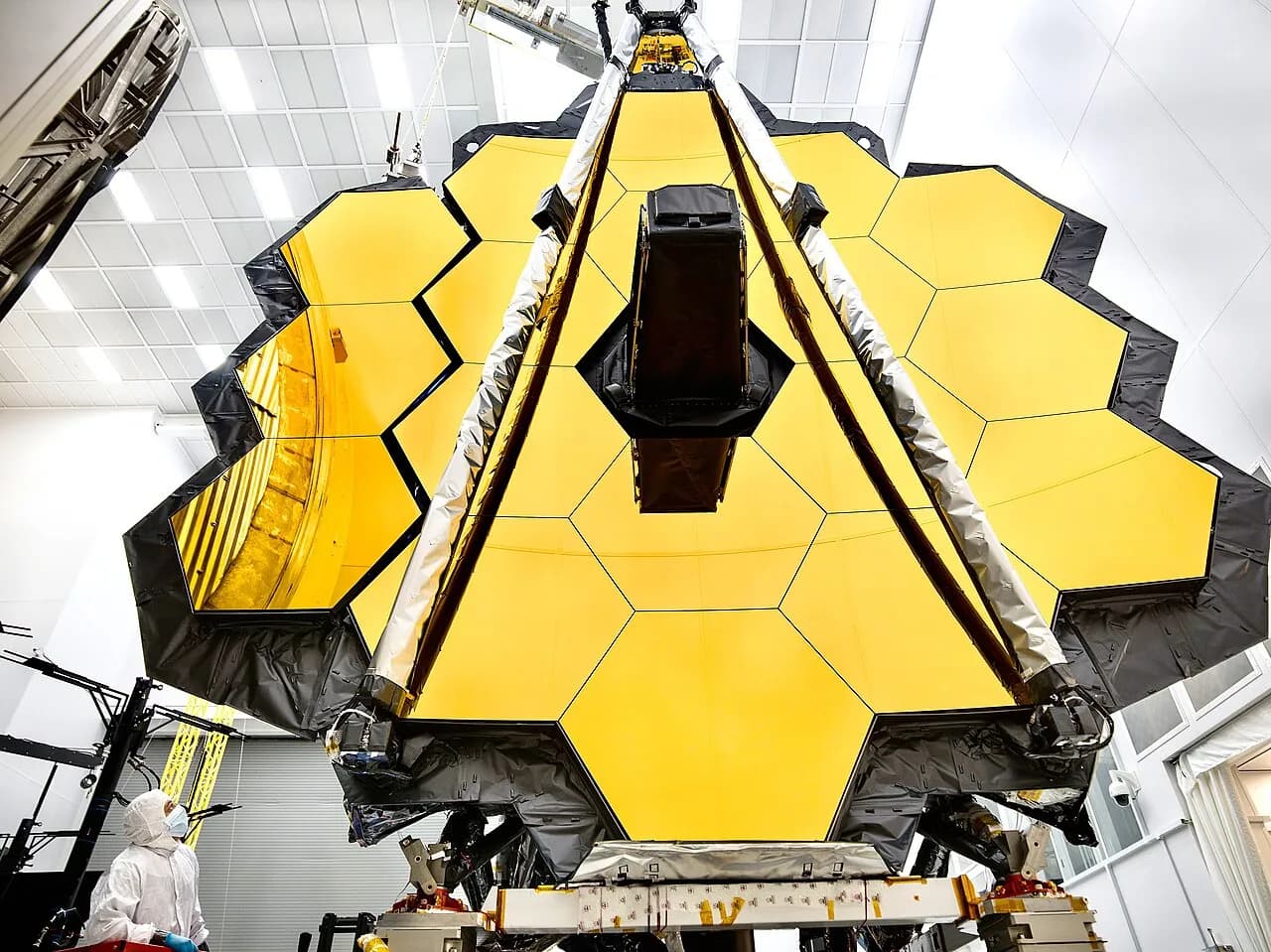The James Webb Space Telescope's primary mirror in a cleanroom, with an engineer nearby