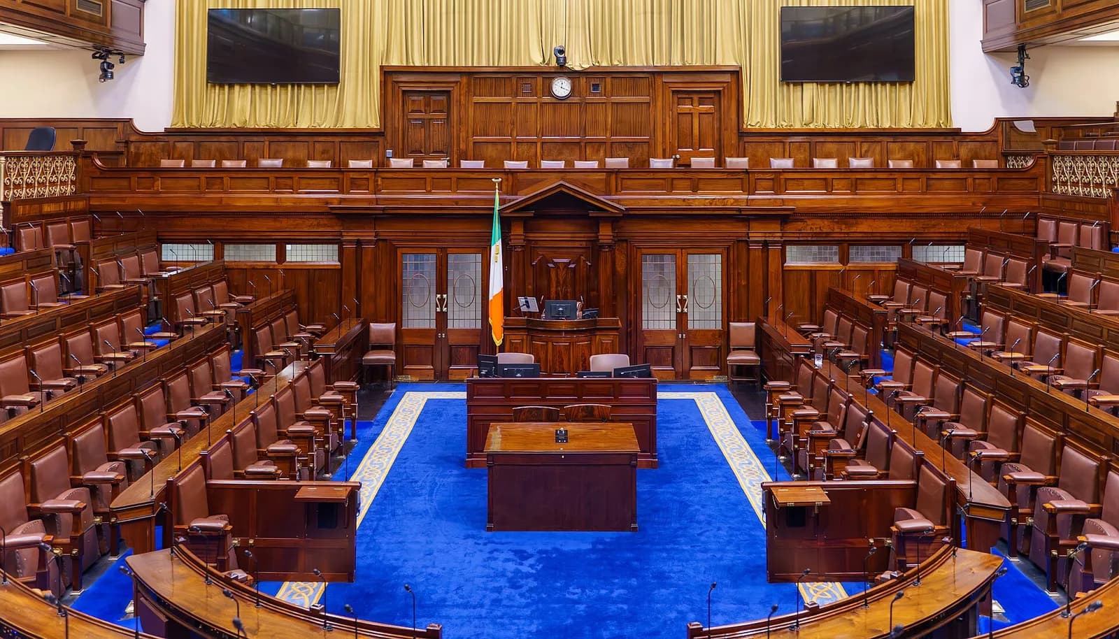 Interior of the Dáil Éireann chamber, showing its curved seating and Speaker’s chair.