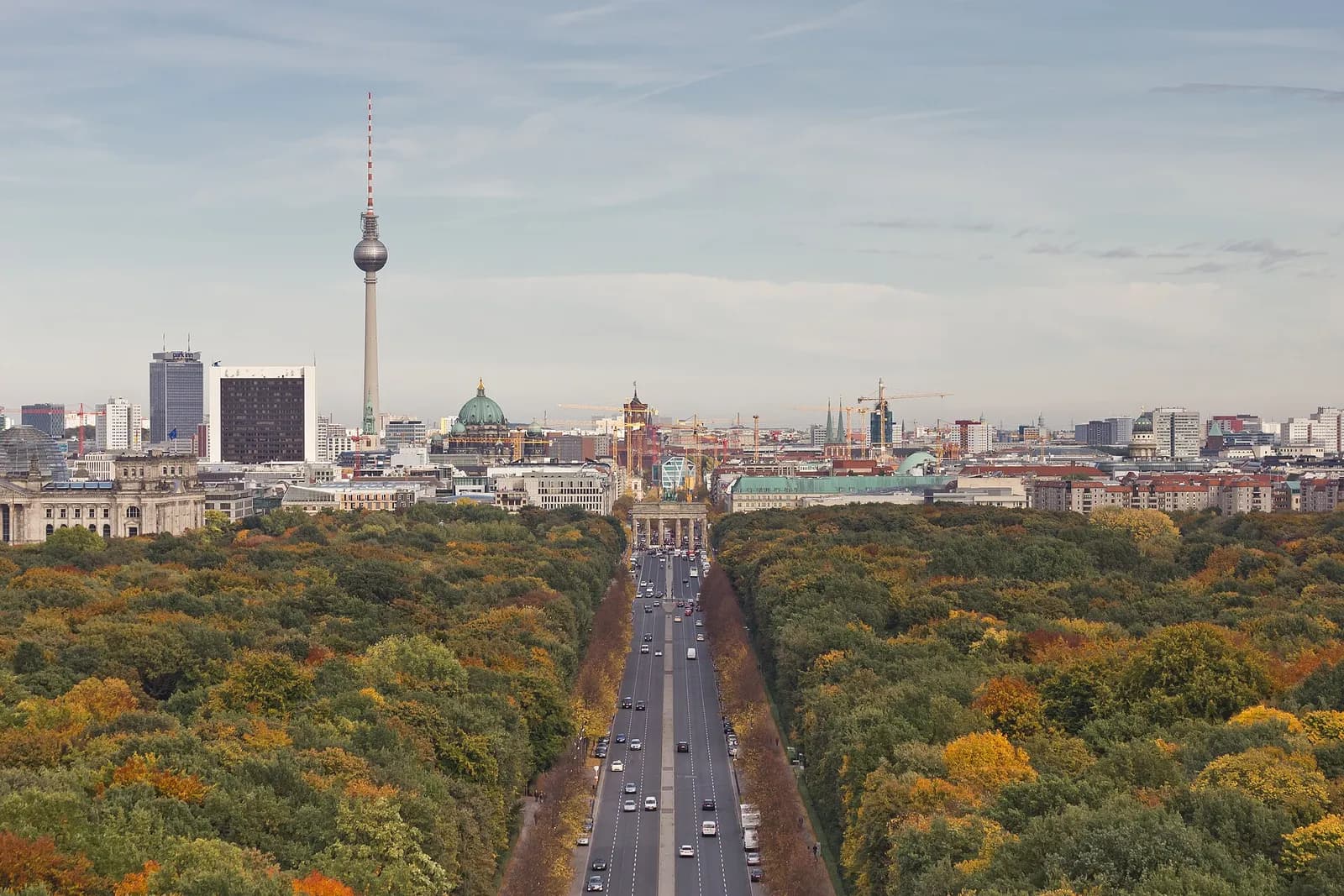 Panoramic view over Berlin from the Victory Column toward Mitte, with the Tiergarten, Brandenburg Gate and TV Tower visible.