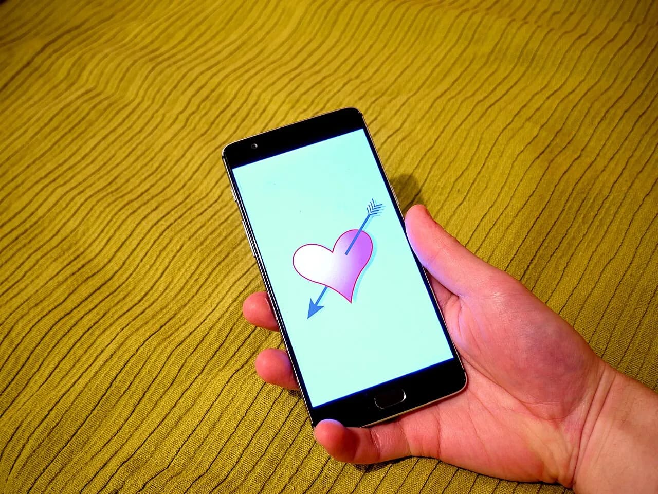 A hand holding a smartphone displaying a dating app