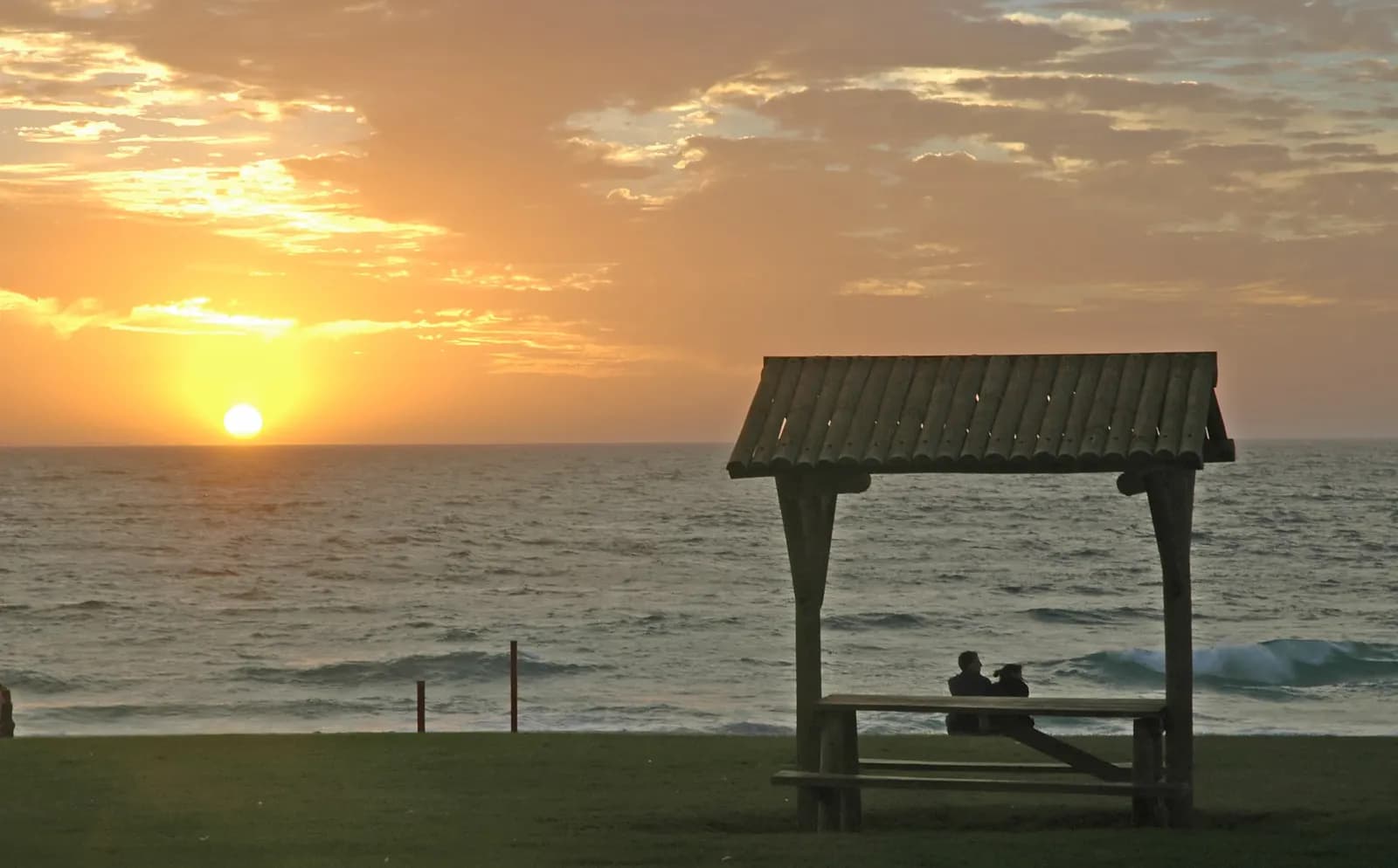 Sunset over the Indian Ocean at City Beach, Perth, with two people silhouetted on the shore