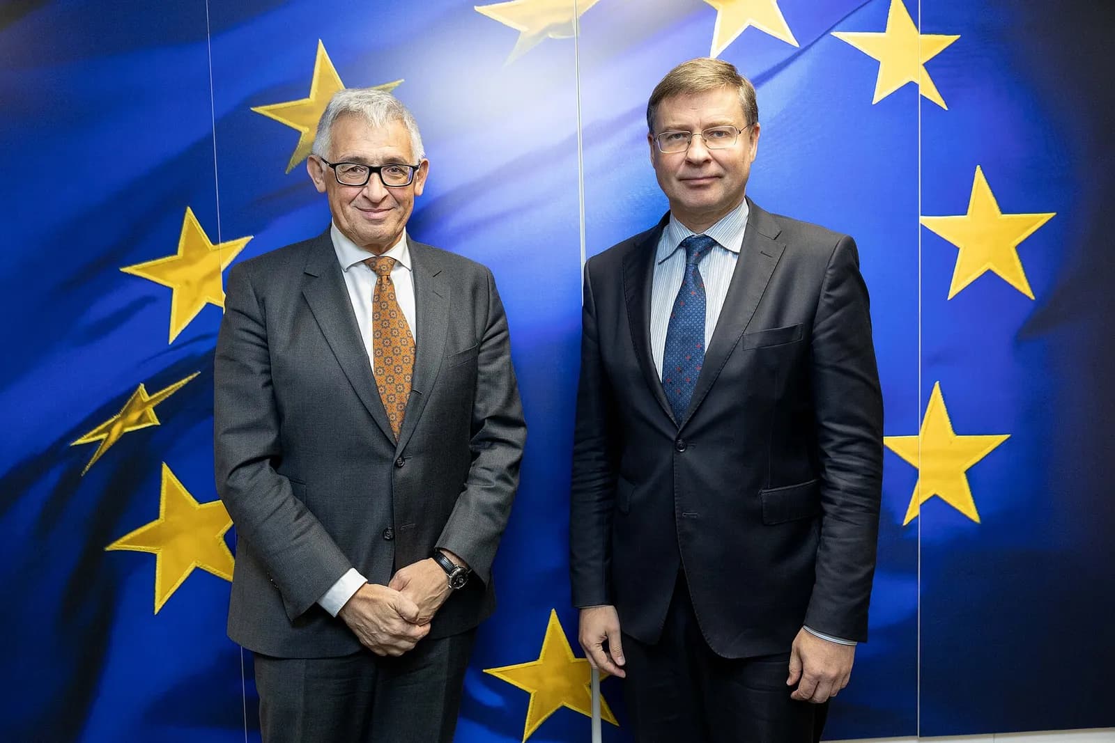Piero Cipollone and Valdis Dombrovskis stand in front of a European Union flag backdrop.