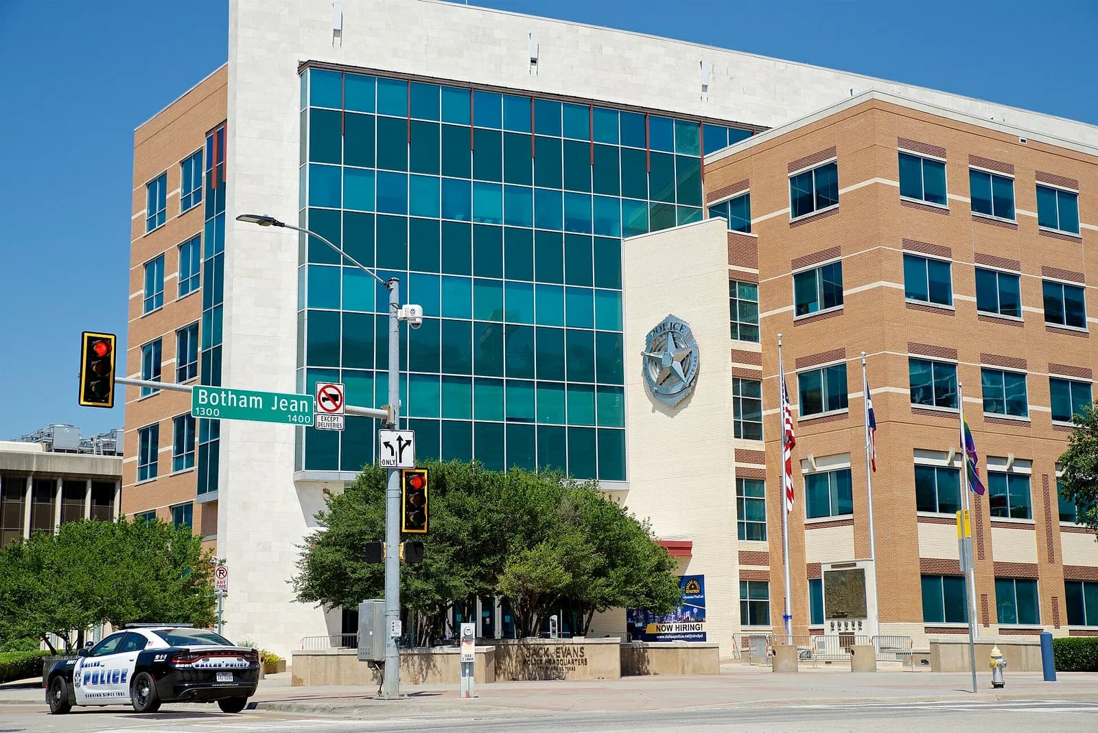 Dallas Police Department headquarters and a street sign for Botham Jean Boulevard, with a police cruiser in front.