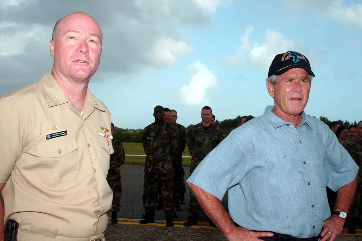 U.S. Navy personnel stand on the flight line at Naval Support Facility Diego Garcia as President George W. Bush and Capt. Greg L. Looney inspect them.