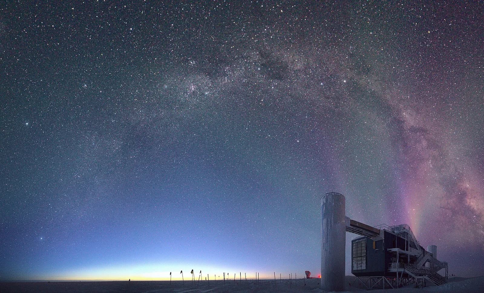 The IceCube Laboratory beneath the Milky Way and auroras near the South Pole.