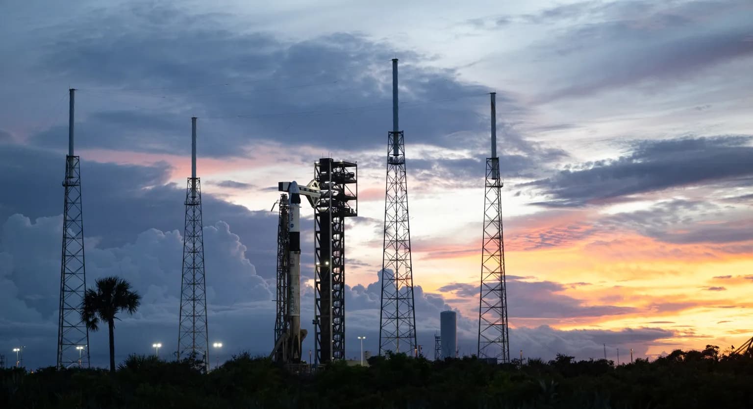 SpaceX Falcon 9 rocket and Crew Dragon spacecraft on the launch pad at sunset