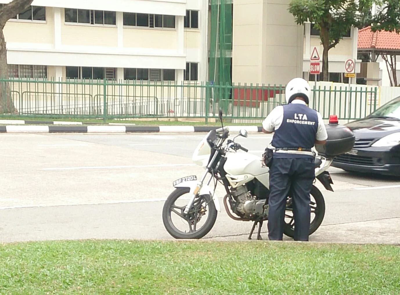 A Land Transport Authority enforcement officer stands beside a motorcycle in Singapore.