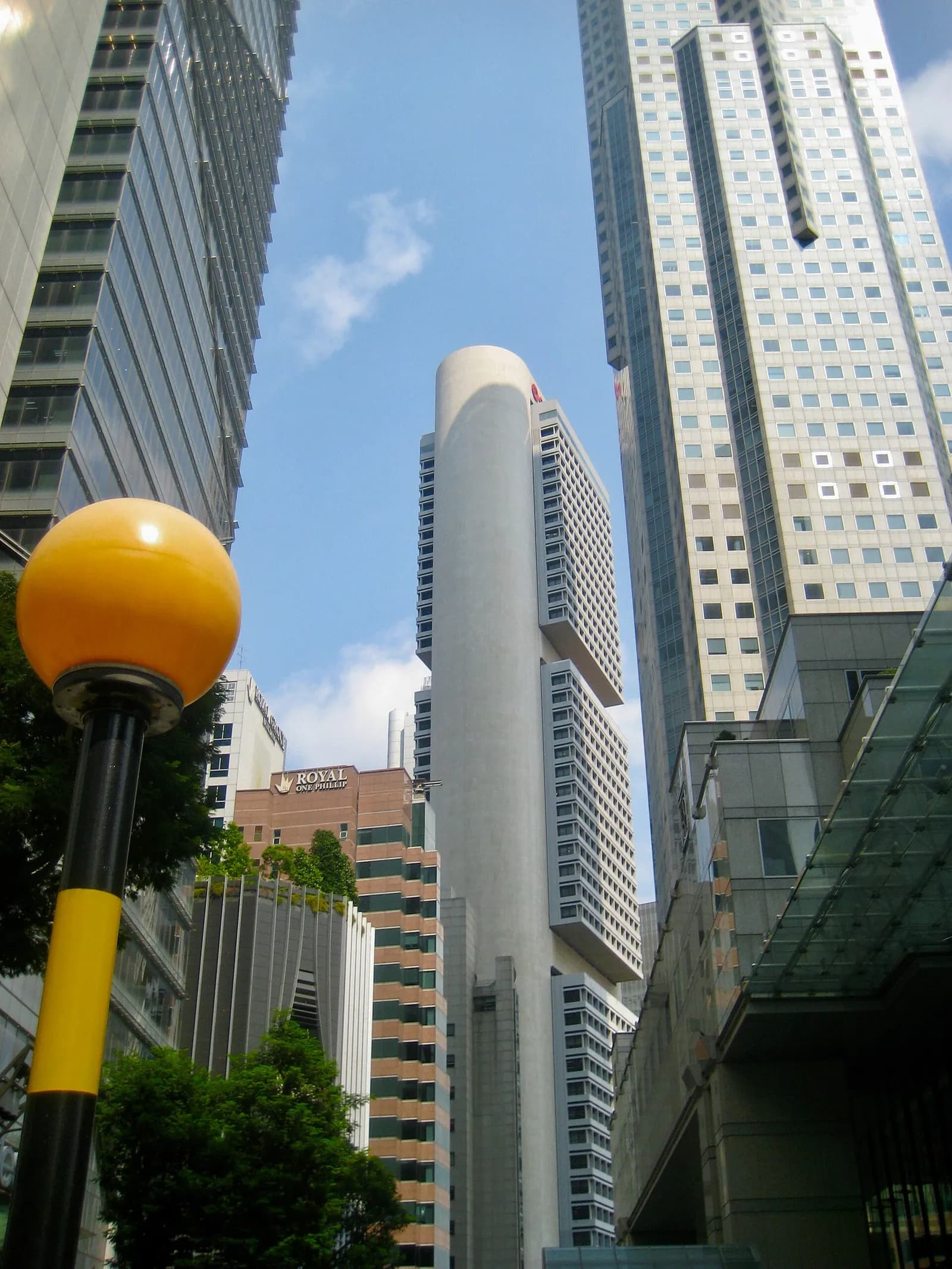 OCBC Centre viewed from the intersection of Bonham Street and Battery Road, with a yellow pedestrian signal pole in the foreground.