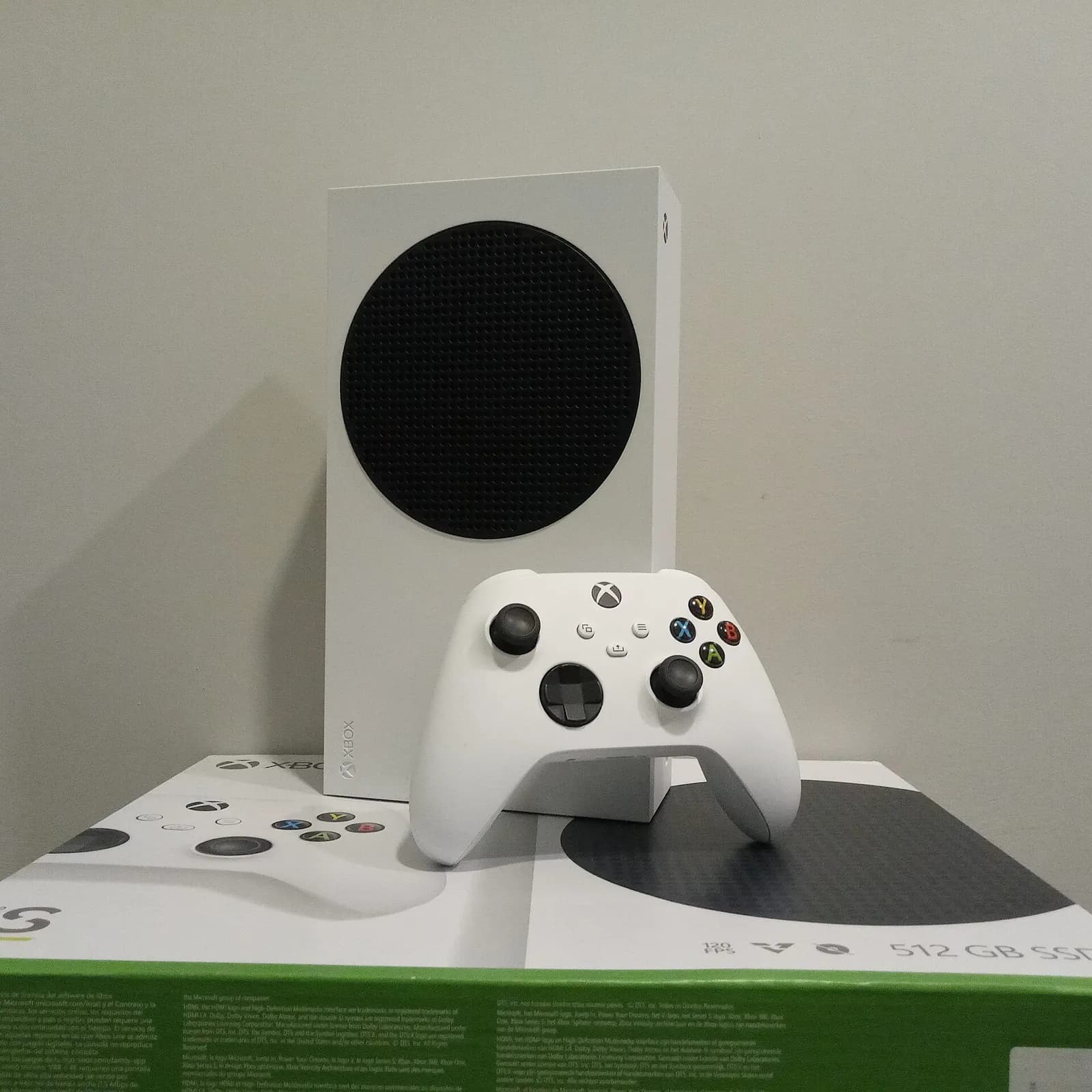 Xbox Series S console standing beside its packaging, with a white wireless controller leaning against it.
