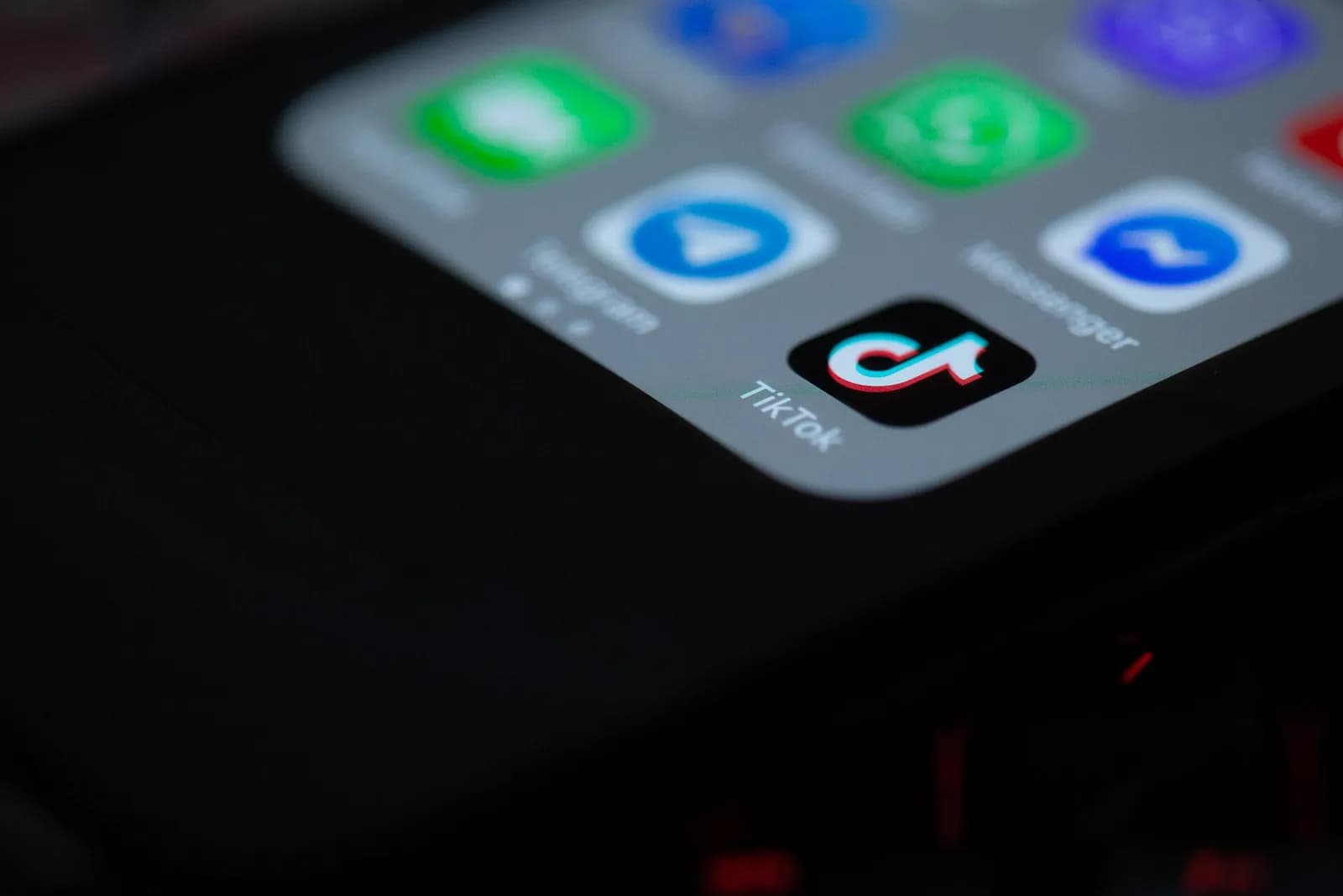 Close-up of a phone screen with the TikTok app icon and label in sharp focus among blurred app icons.