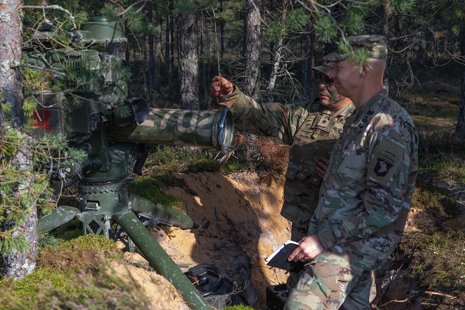 Maj. Gen. Brett Sylvia speaks with a U.S. Army soldier beside a TOW missile system during a training exercise.