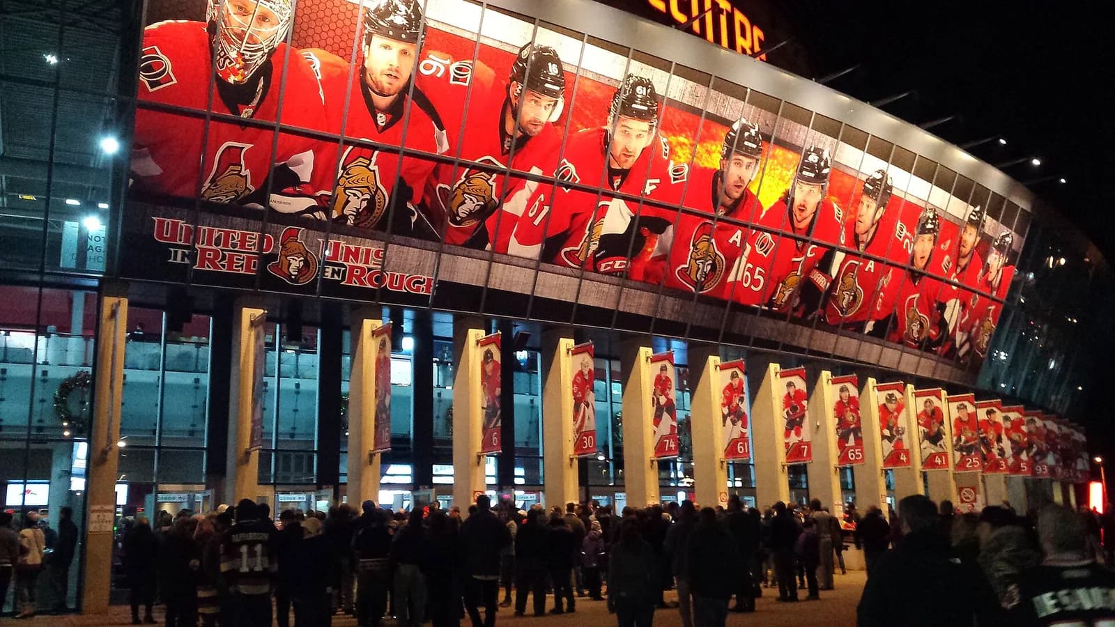 Crowd outside the Canadian Tire Centre beneath Ottawa Senators player displays.