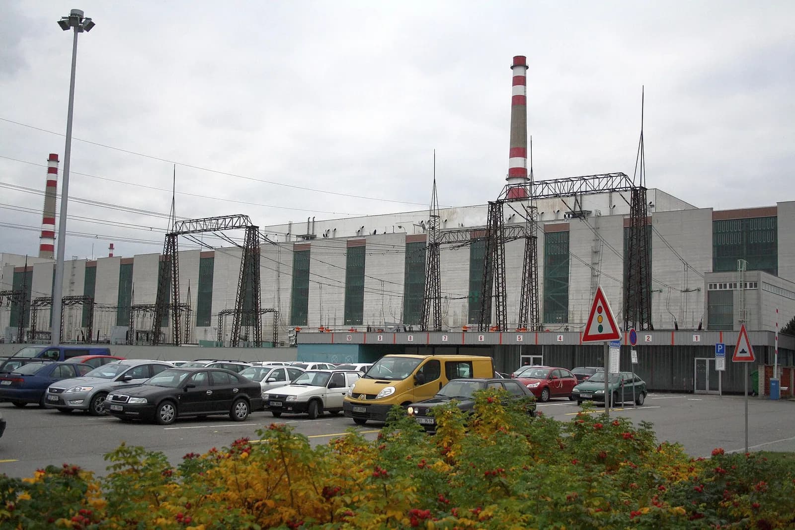 Exterior of the Dukovany Nuclear Power Station, with plant buildings, smokestacks and a car park.